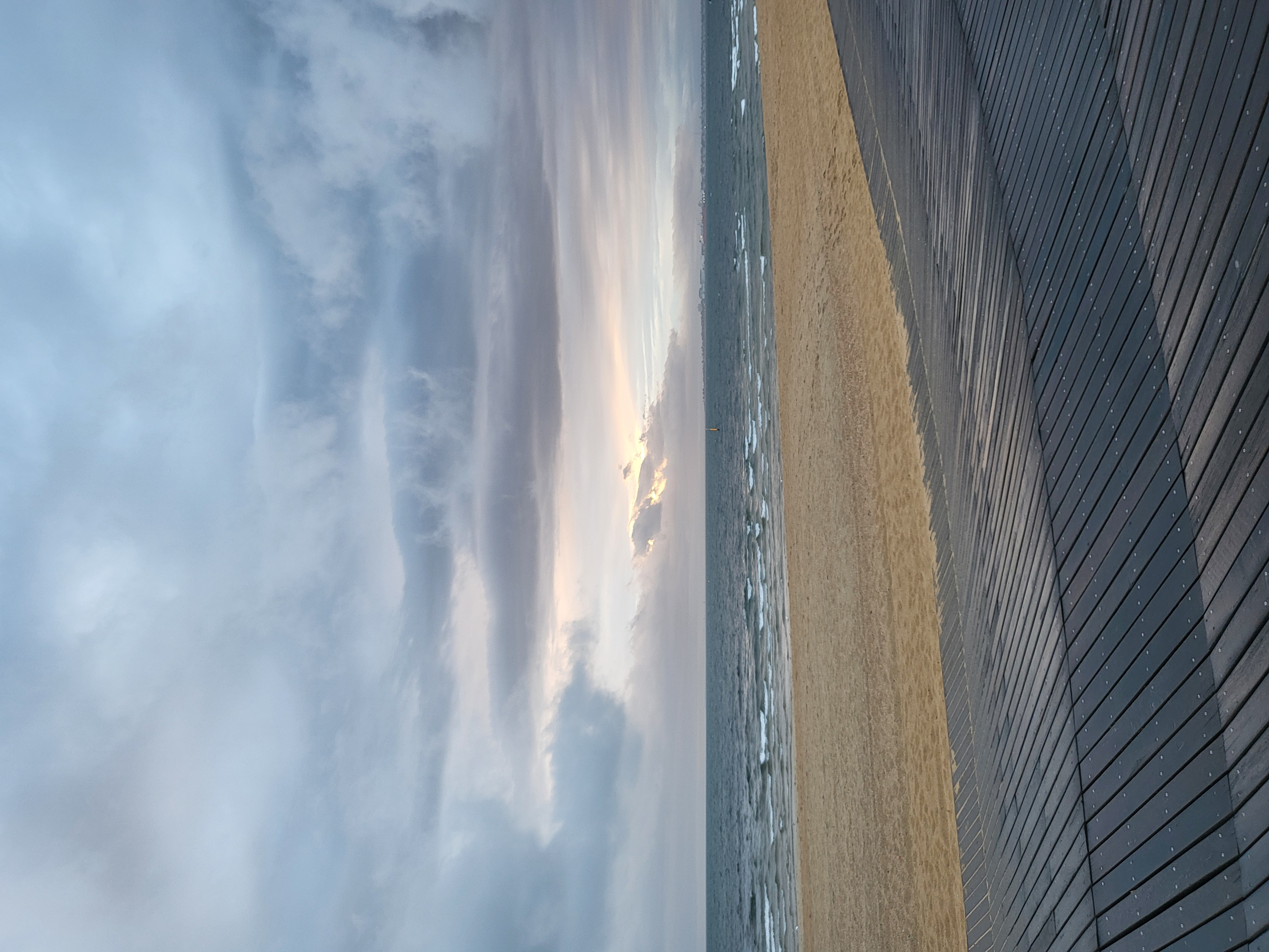 grey clouds over a grey ocean, wet sand and a grey boardwalk